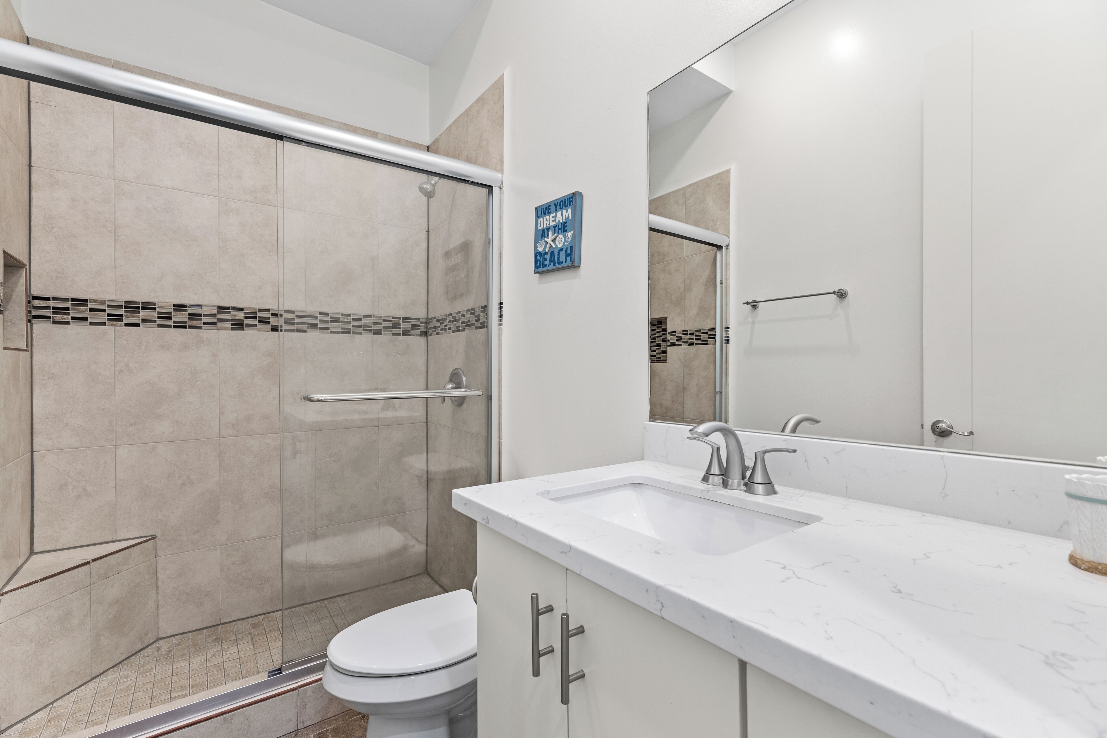 A modern bathroom with a shower, toilet, and sink.
