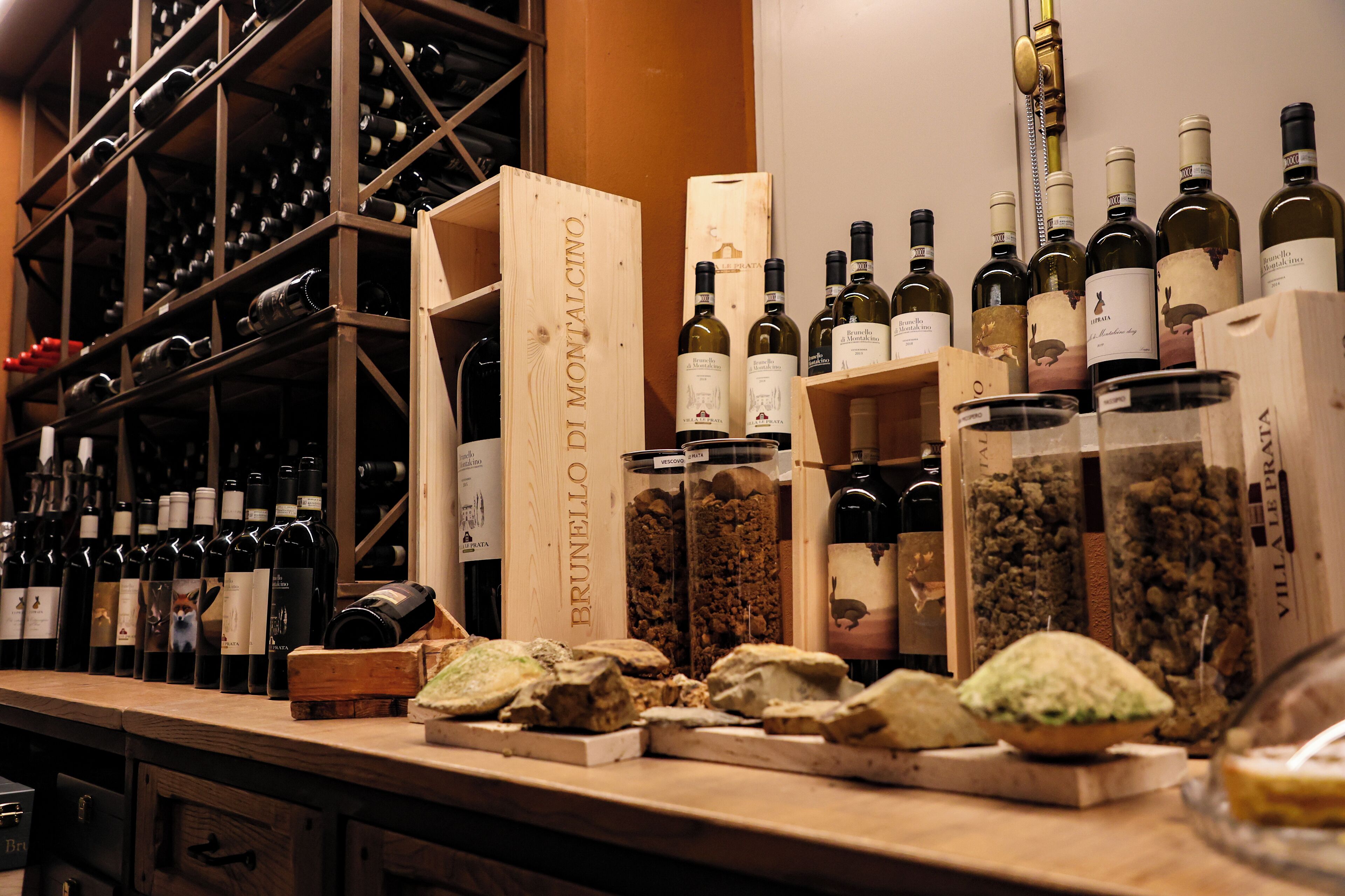 Una bodega con estanterías y repisas de madera llenas de botellas de vino.