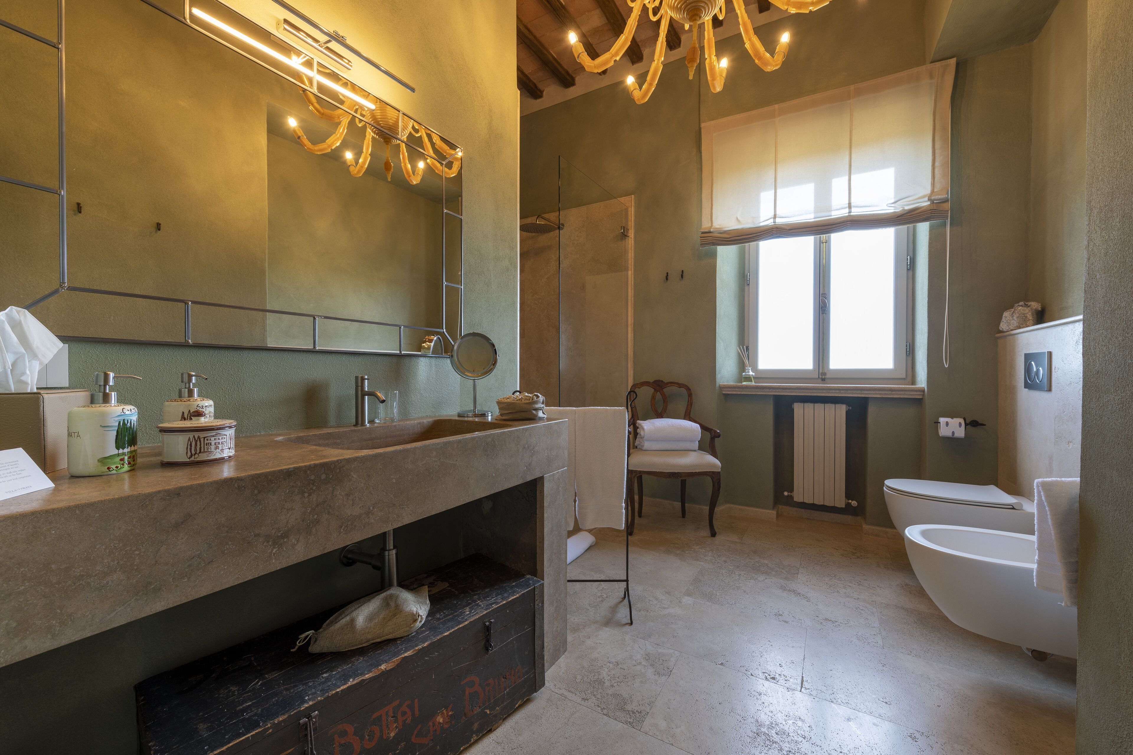 Une salle de bain avec un grand miroir, un lavabo avec des articles de toilette, une douche et des toilettes.