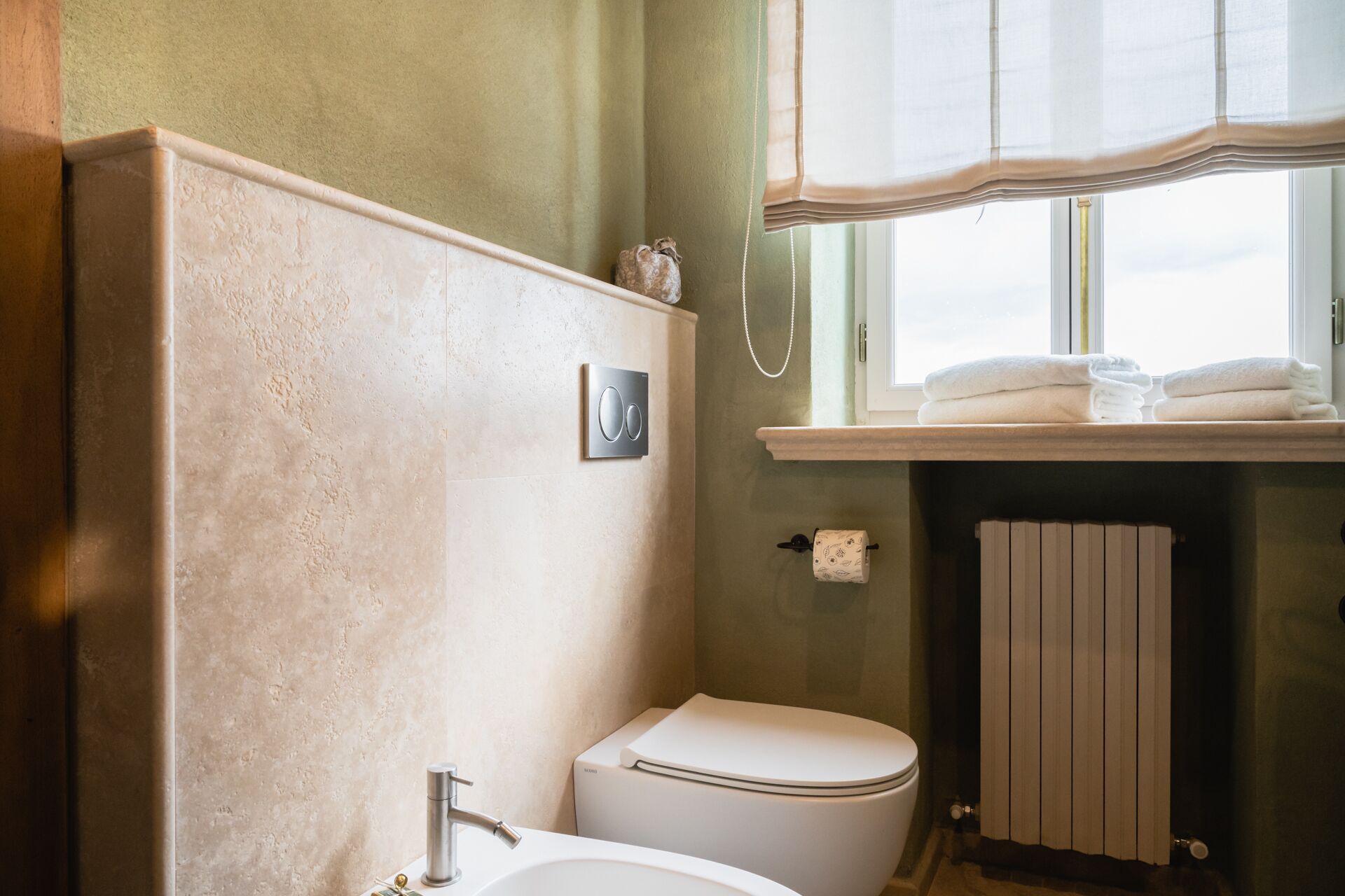 A bathroom with a toilet, a sink, and a window with a towel rack.