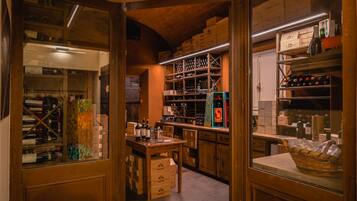 A wine cellar with wooden shelves and boxes, a counter with bottles, and a basket on a table.