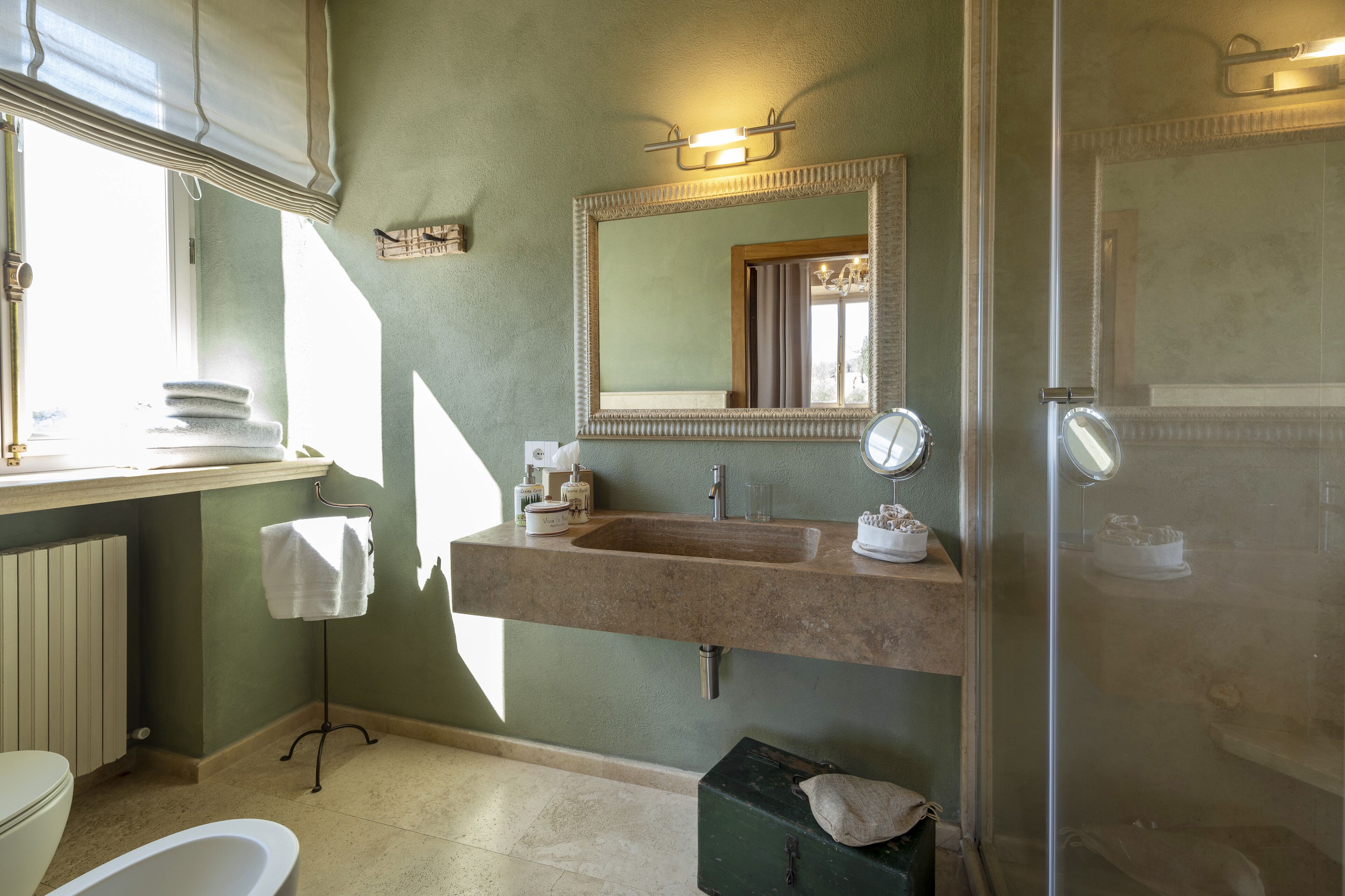 A bathroom with a large sink, a mirror, a towel rack, and a shower area.