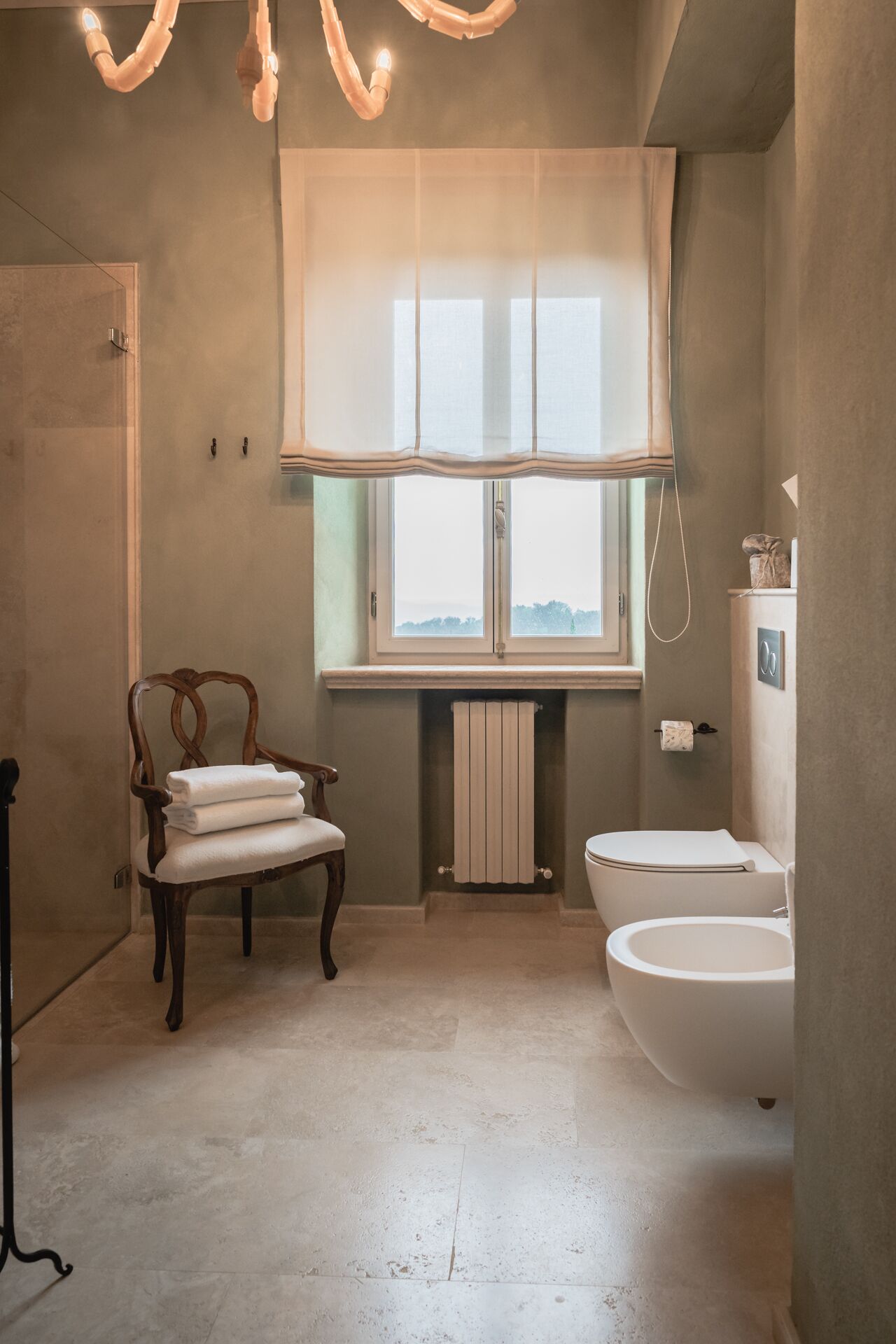 Une salle de bain avec une chaise en bois, des toilettes et un radiateur.