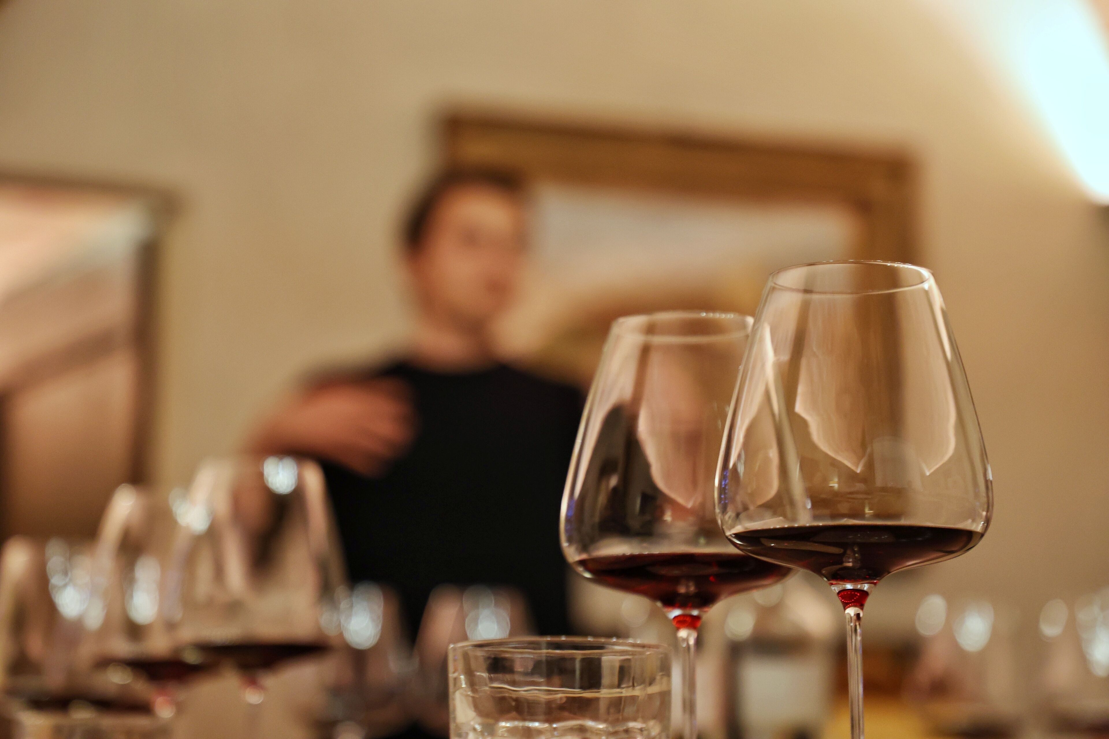 Primer plano de copas de vino sobre un fondo desenfocado de una persona.