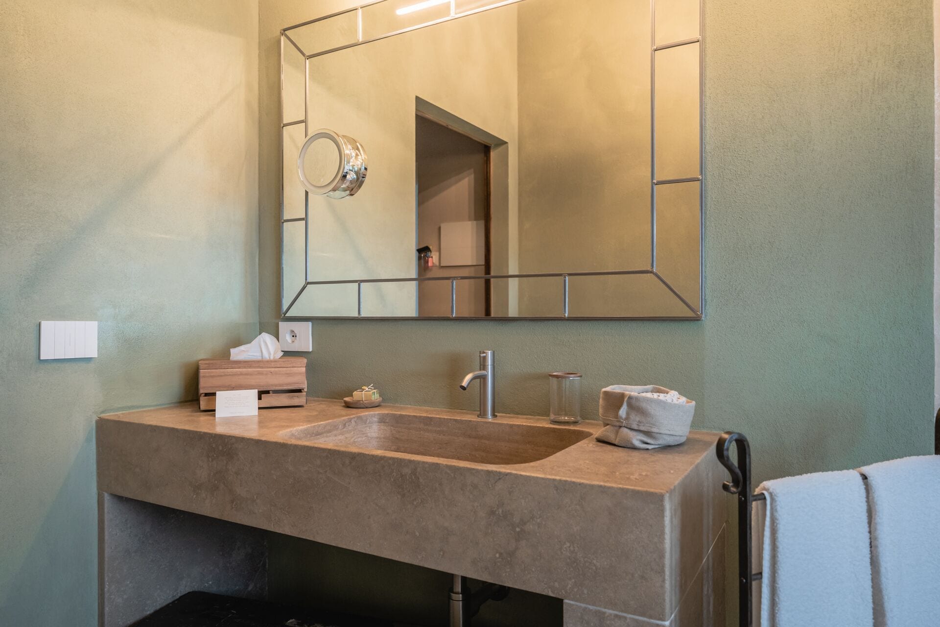 A bathroom with a large mirror, a sink, and a towel rack.