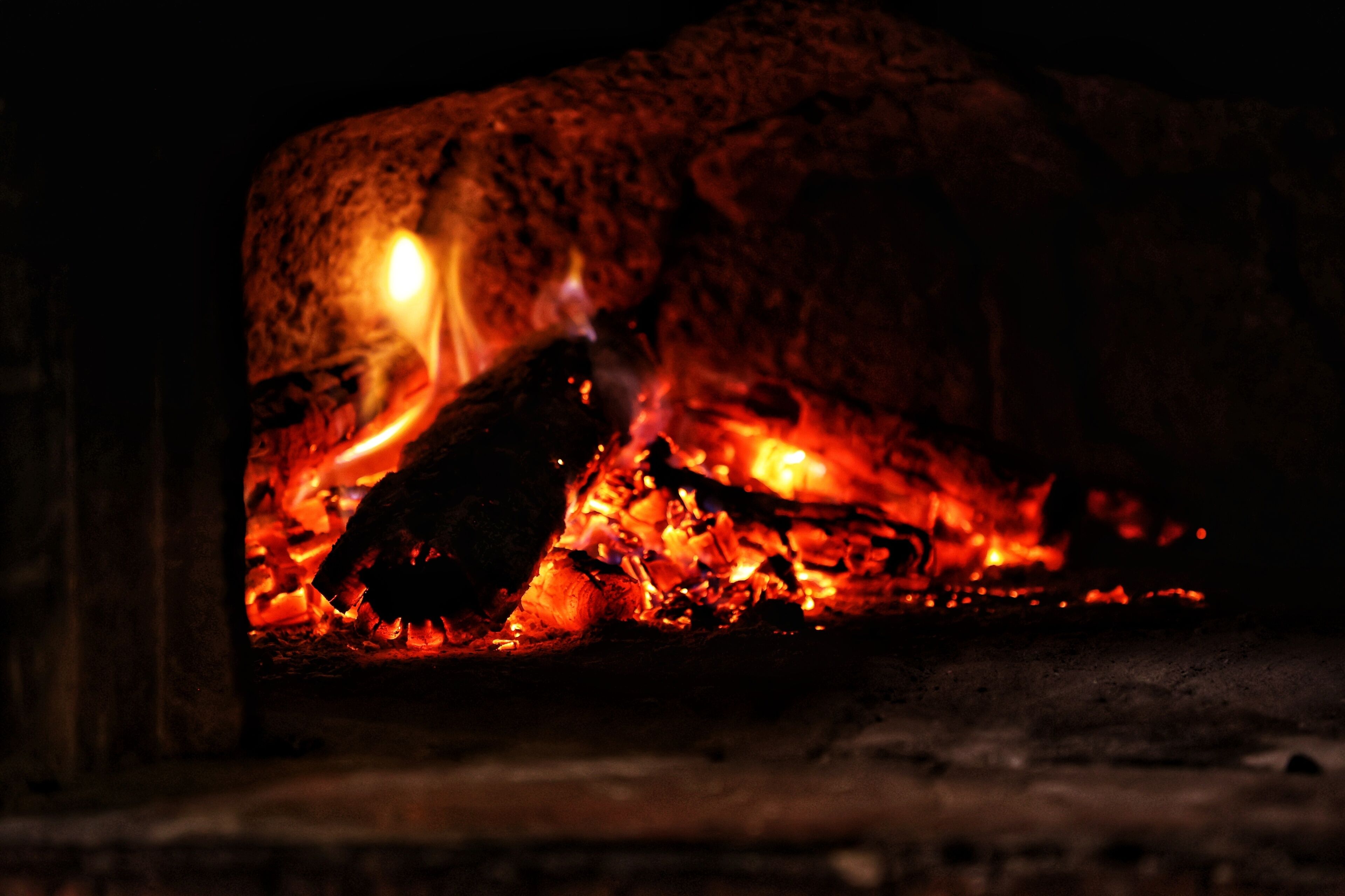 Primer plano de un fuego ardiendo en una chimenea, mostrando troncos y brasas incandescentes.