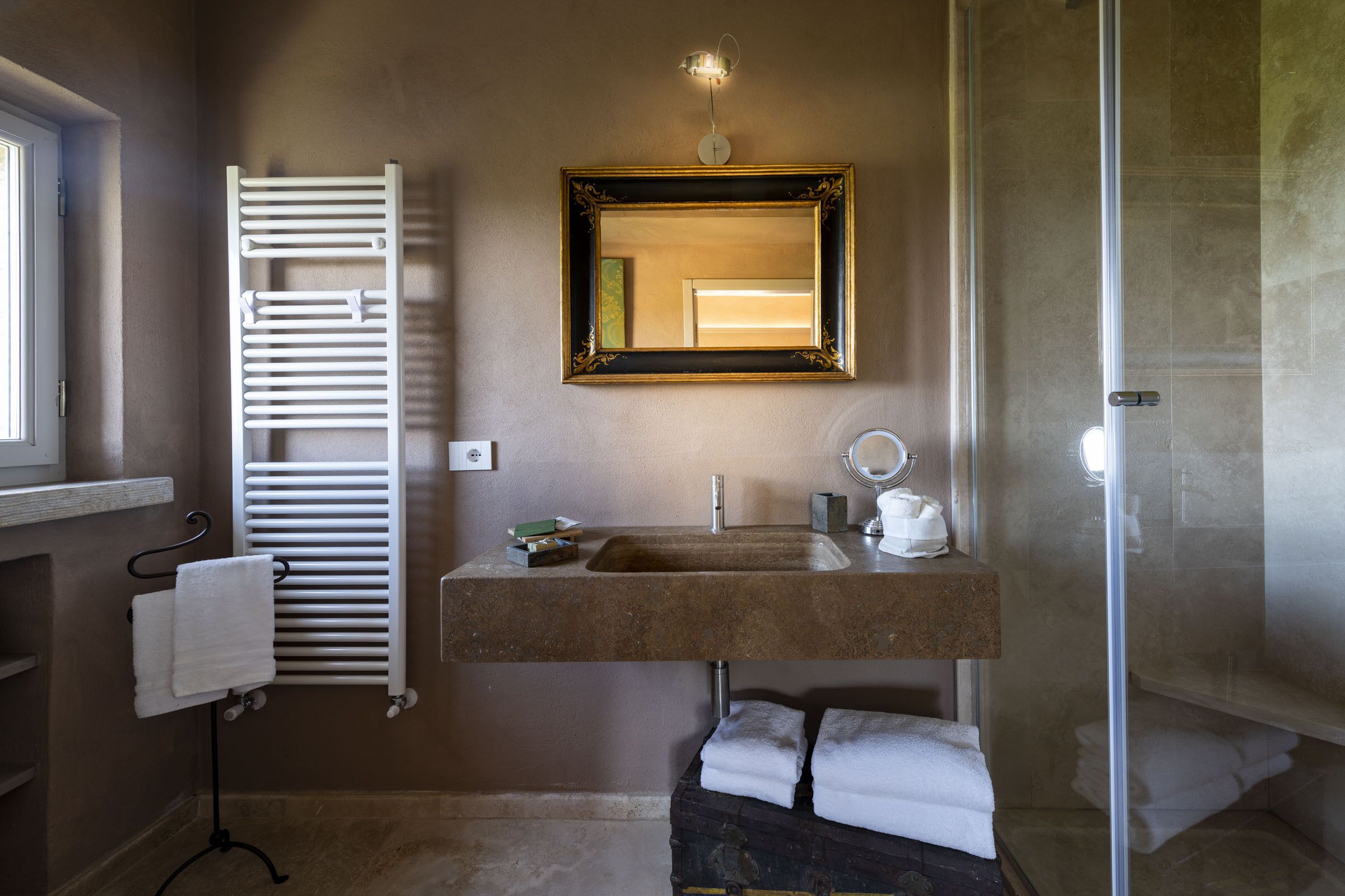 Un baño con toallero blanco, lavamanos con espejo y zona de ducha.