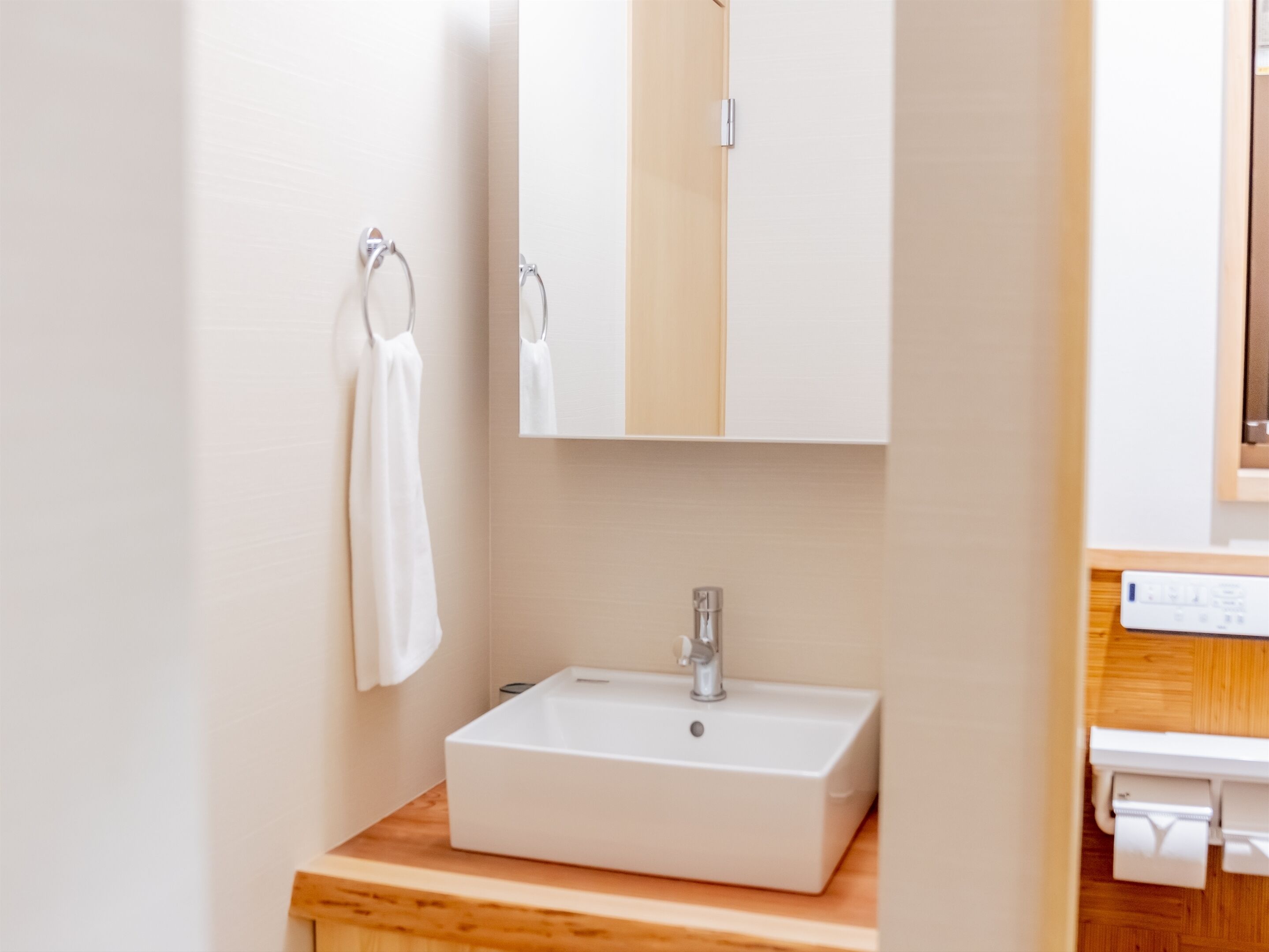 A bathroom with a white sink, a mirror, and a towel hanging on a rack.