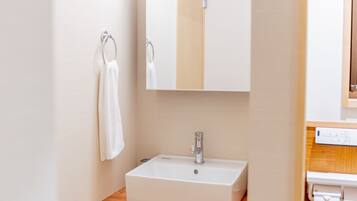 A bathroom with a white sink, a mirror, and a towel hanging on a rack.