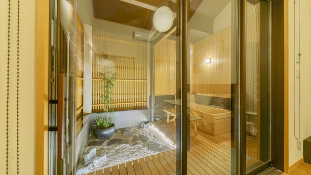 A modern interior with a wooden floor, a seating area with a bench, and a potted plant.