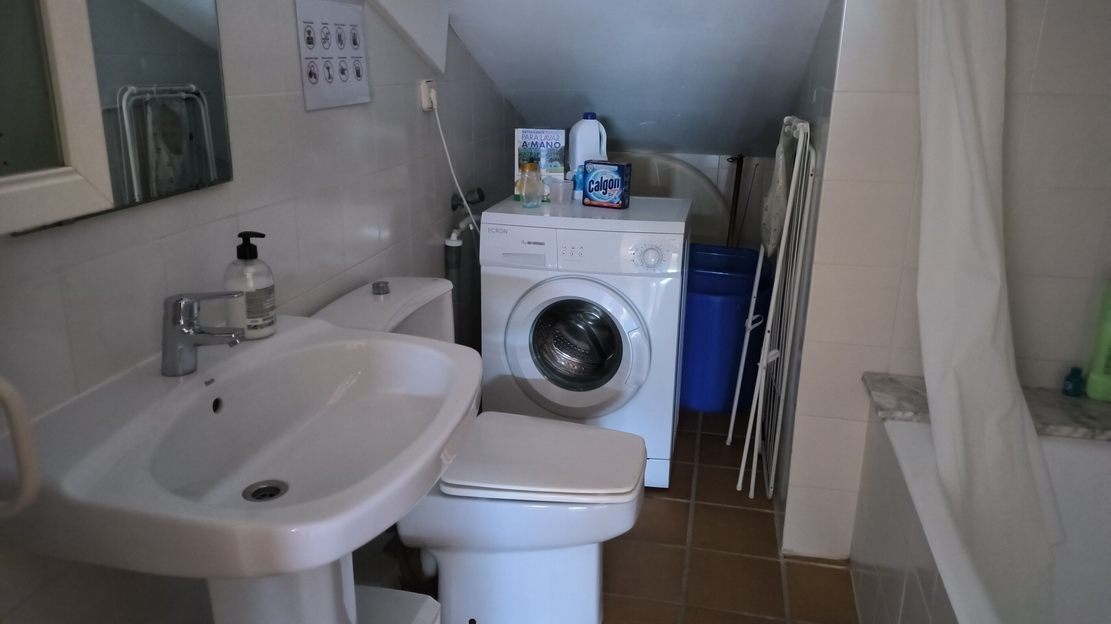 A compact bathroom with a sink, toilet, and washing machine.