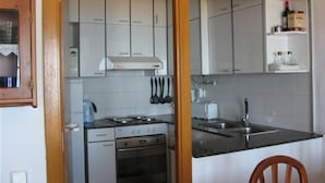 Eine Küche mit weißen Schränken, einem Herd, einem Spülbecken und einem Stuhl.