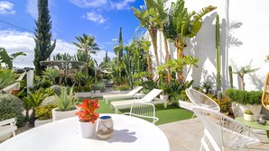 A patio with a white table, chairs, and potted plants.