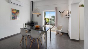 A modern dining area with a glass table, white chairs, and a hanging light fixture.