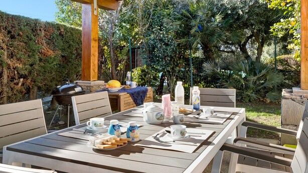 Un espace de restauration en plein air avec une table dressée pour le petit-déjeuner, comprenant des assiettes, des tasses et un gril.