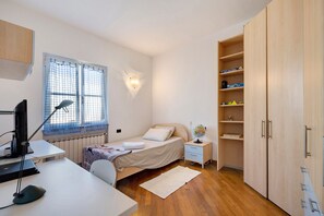 Une chambre à coucher comprenant un lit, un bureau, une chaise, une lampe et une armoire.