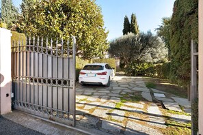 Une allée fermée par un portail menant à une voiture garée.