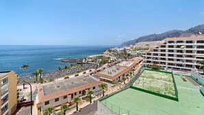 Een hotel aan de kust met meerdere verdiepingen, een tennisbaan en uitzicht op zee.