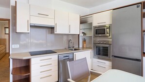 Een moderne keuken met een vaatwasser, oven, magnetron en een roestvrijstalen koelkast.