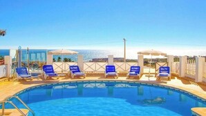 A pool with blue lounge chairs and umbrellas, overlooking a clear blue sky and a distant view. - Villa 'Albuar' with Sea View, Pool, Garden & Wi-Fi (São Rafael)
