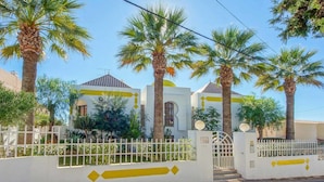 A residential building with a white exterior, palm trees, and a gated entrance. - Villa 'Albuar' with Sea View, Pool, Garden & Wi-Fi (São Rafael)