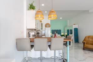 Een moderne keuken met witte kasten, een houten kookeiland met barkrukken en hangende wilgentaklampen.
