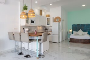 A modern kitchen with white cabinets, a central island with bar stools, and a teal accent wall.