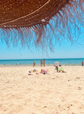 A beach with people, a straw umbrella, and beach towels. - Apartment 'Casa Maria' with Balcony, A/C & Wi-Fi (Faro)