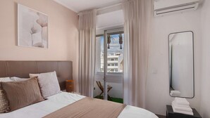 Een hotelkamer met een bed, nachtkastje, spiegel en uitzicht door een deur.