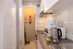 Une cuisine moderne équipée d’un four à micro-ondes, d’une bouilloire et d’une machine à café, d’un évier avec un égouttoir et d’une porte signalant les issues de secours.
