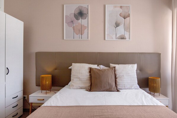 Une chambre à coucher comprenant un lit, des tables de chevet, une armoire et deux œuvres d’art accrochées au mur.