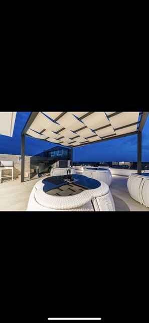 A modern outdoor seating area with a pool table, cushioned seating, and a covered patio. - GrandPalazzo luxury apartments with rooftop swimming pool (Vir)
