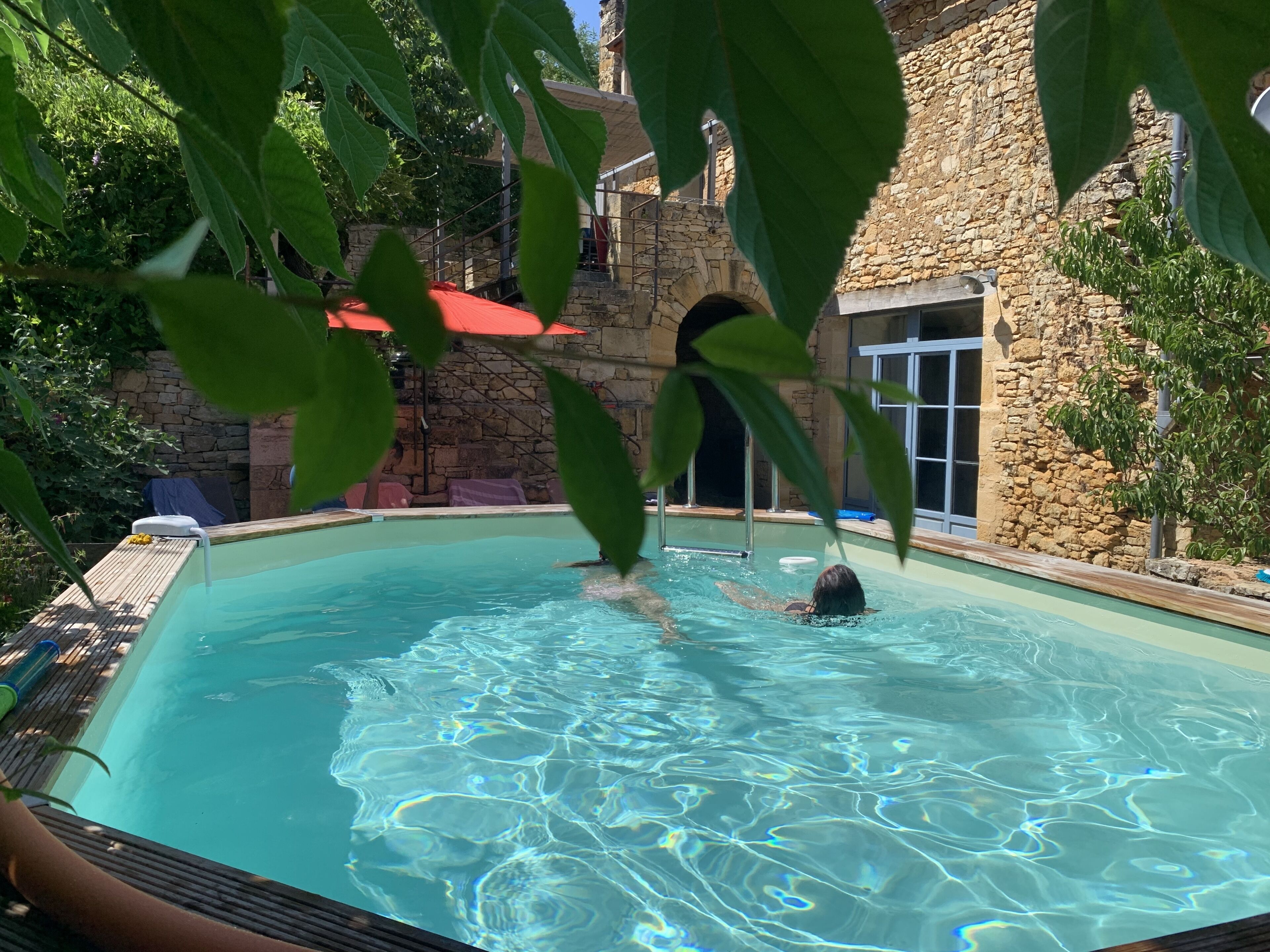 A swimming pool with clear water, surrounded by stone walls and greenery.