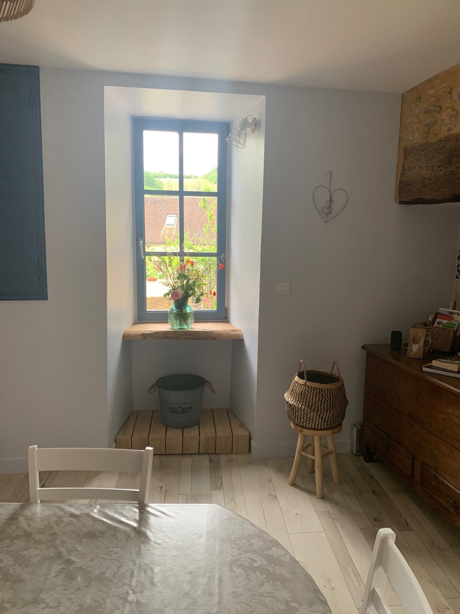 Une pièce confortable avec une fenêtre, un banc en bois, une table et une commode.