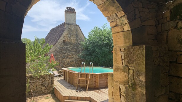 A stone building with a wooden deck and a hot tub. - Authentic stone house in a typical village at the foot of a castle! (Berbiguières)