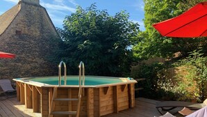 A wooden hot tub on a deck with a stone structure in the background. - Authentic stone house in a typical village at the foot of a castle! (Berbiguières)