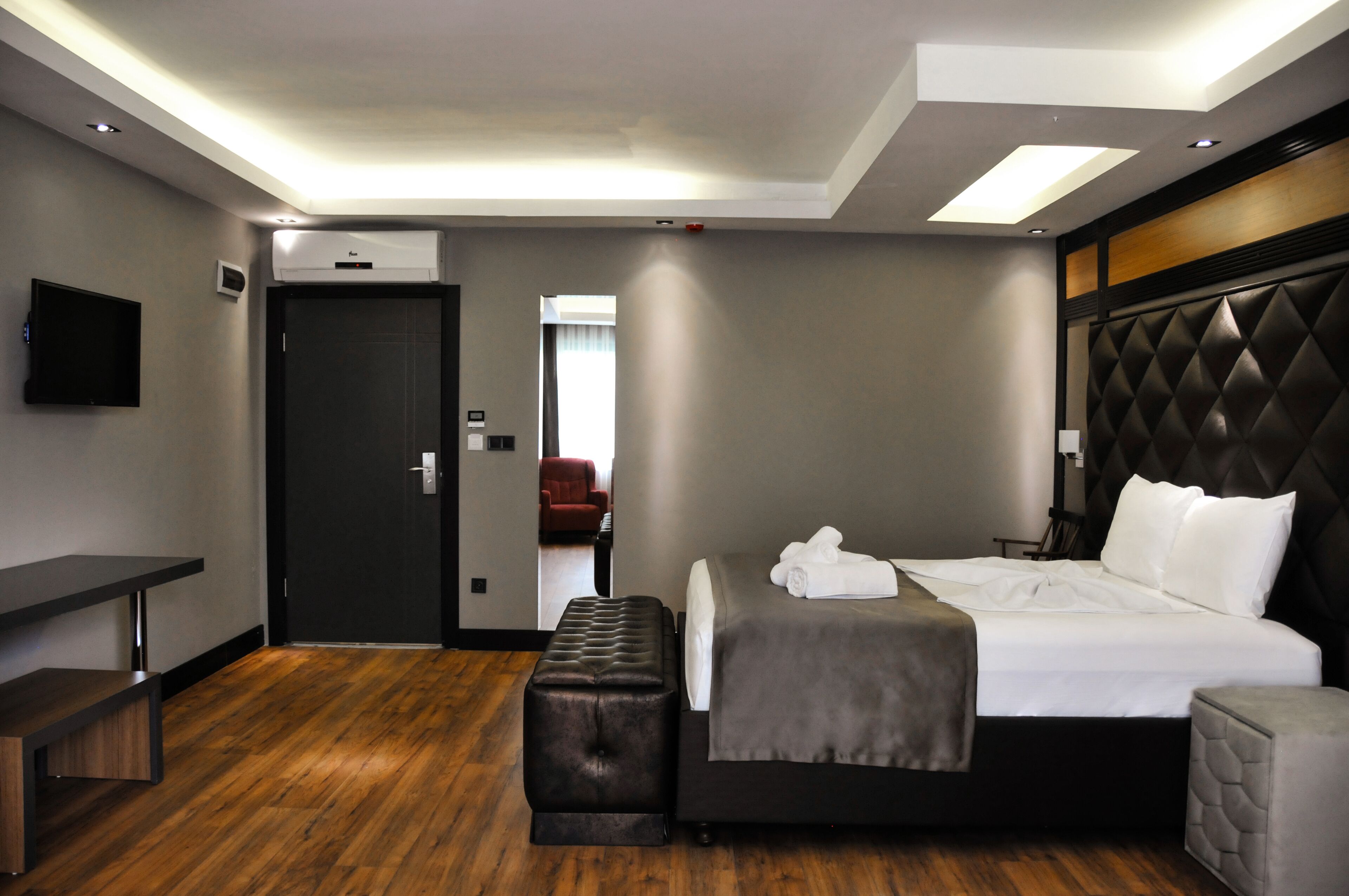Een moderne hotelkamer met een groot bed, een bureau, een bankje en een televisie aan de muur.