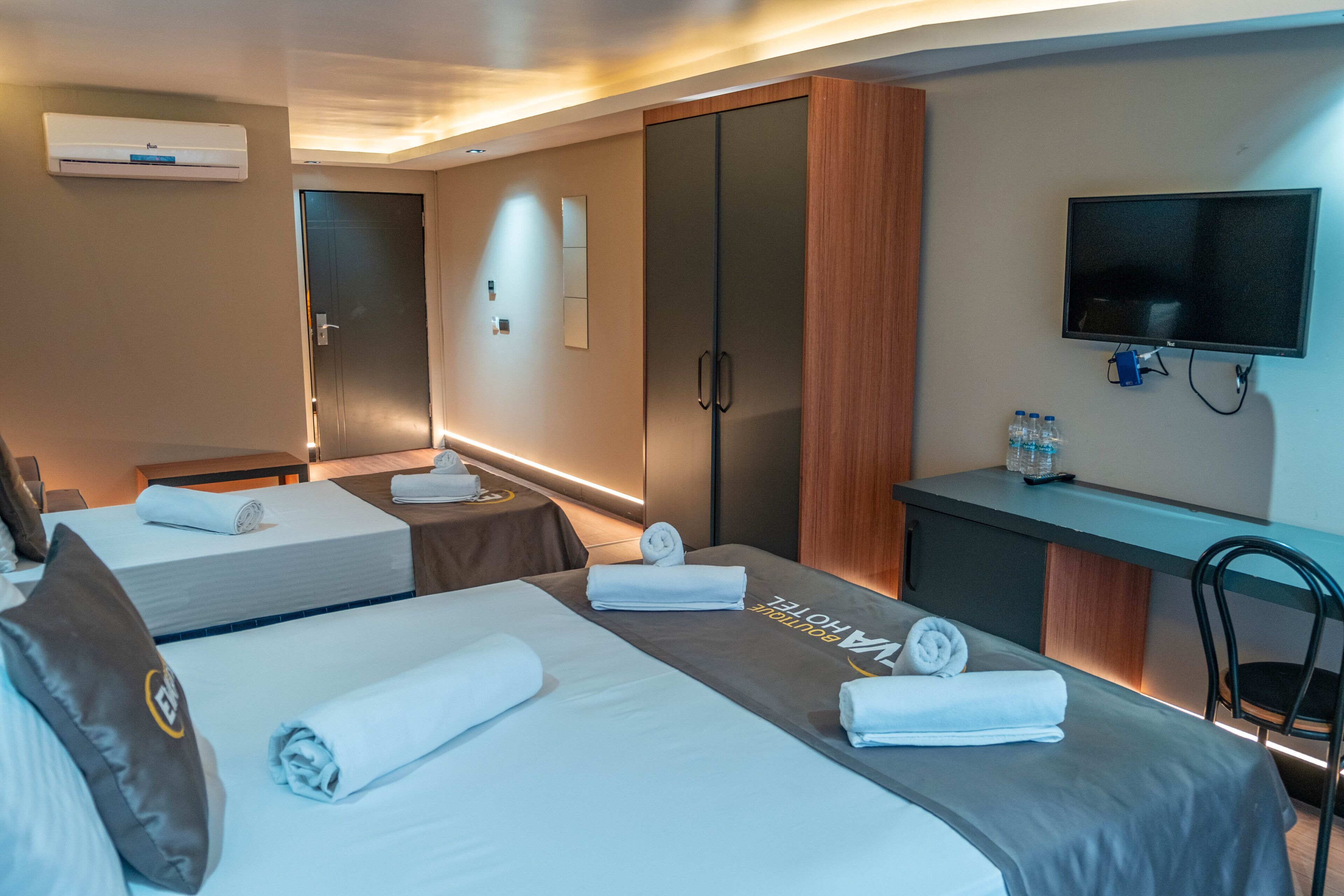 Una habitación de hotel con dos camas, un escritorio, un televisor y un minibar.