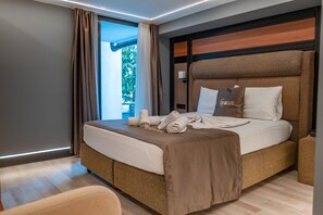 A modern hotel room with a large bed, a bedside table, and a view of greenery outside. - Eva Boutique Hotel Spa (Konyaalti)