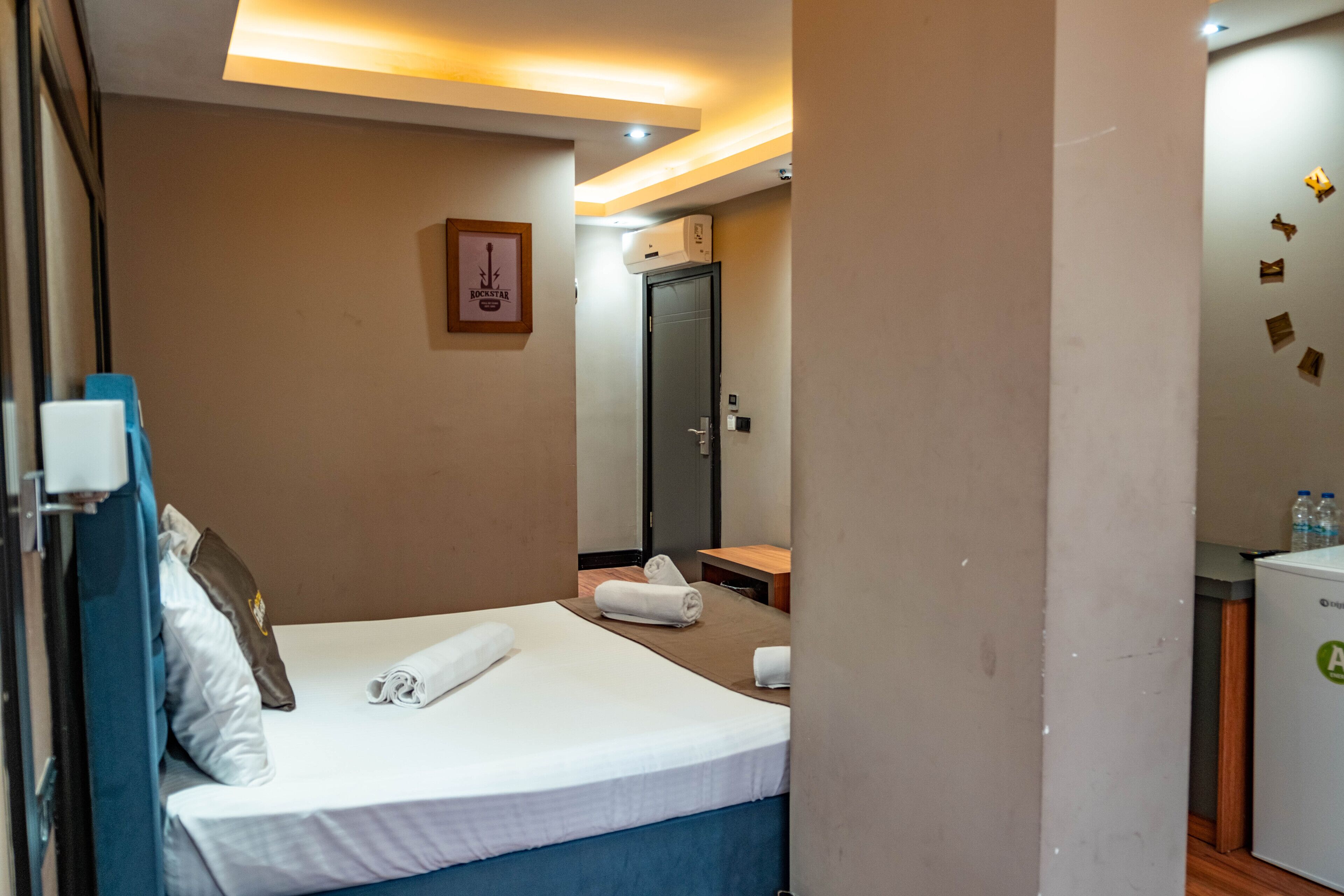 Une chambre d’hôtel équipée d’un lit, d’un bureau, d’une chaise, d’une armoire et d’un petit réfrigérateur.