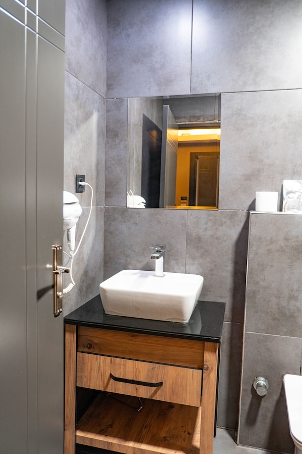 Een moderne badkamer met een wit wastafelmeubel, een houten kastje en een spiegel.