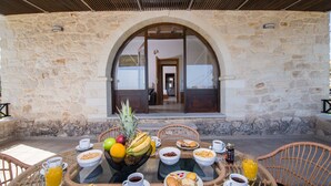 Ein Frühstücksbuffet mit Tisch, Stühlen und einer Wand aus Stein im Hintergrund.