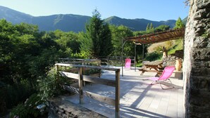 A patio with a wooden deck, a stone wall, and a view of mountains.