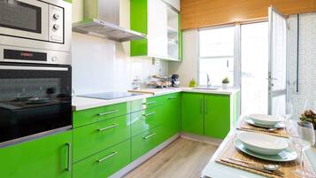 Une cuisine moderne avec des meubles de couleur verte, un four encastré et une fenêtre qui laisse entrer la lumière naturelle.