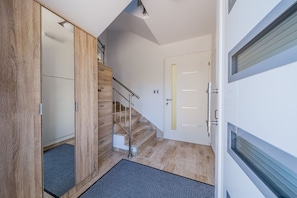 Un interior moderno con un armario de madera, una escalera y una puerta blanca.