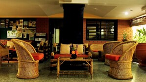 A cozy lounge area with wicker furniture, a coffee table, and a world map on the wall. - The Green Path (Bengaluru)