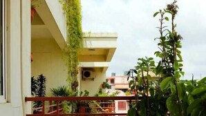 A balcony with a metal railing, potted plants, and a view of the surrounding buildings. - The Green Path (Bengaluru)