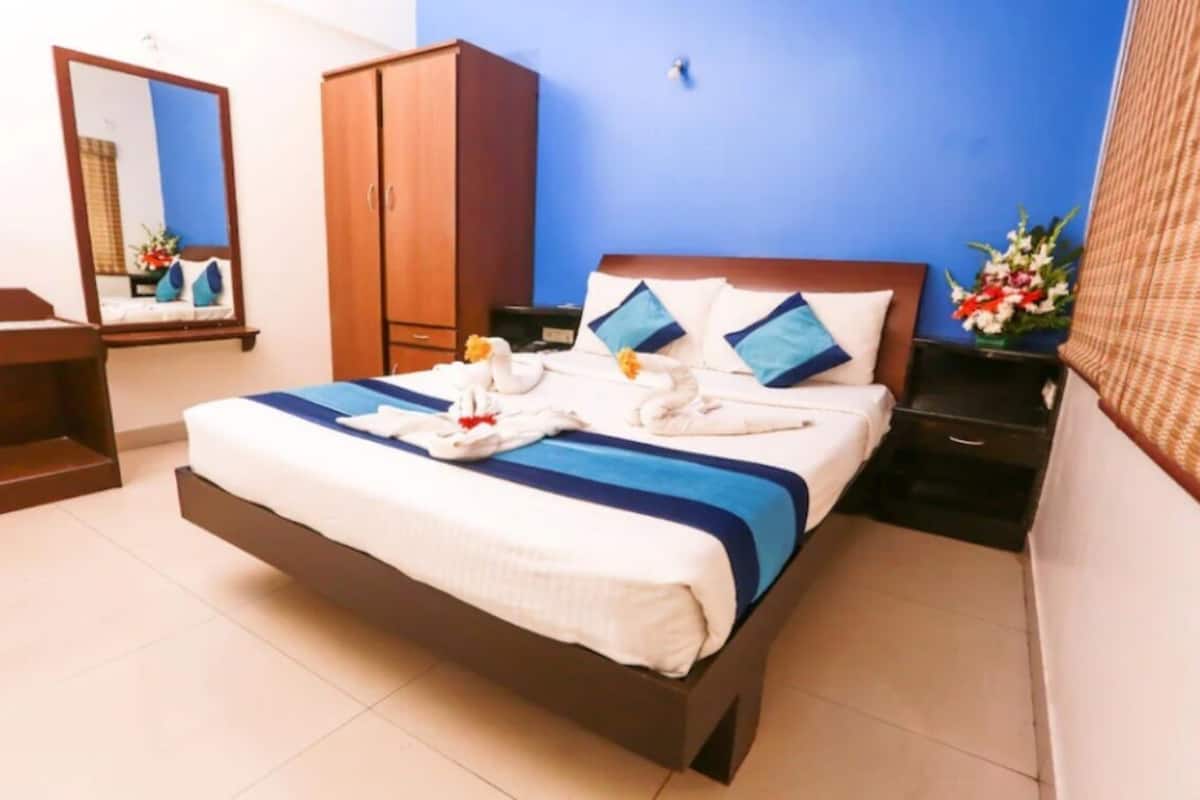 A hotel room with a bed, a wardrobe, a desk, and a mirror.
