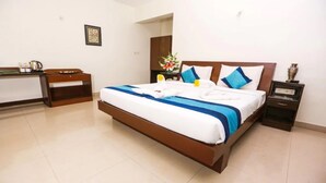 A neatly arranged hotel room with a large bed, a desk, and a nightstand. - The Green Path (Bengaluru)