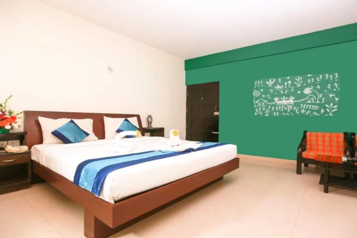 A hotel room with a bed, nightstands, a green wall, and a sofa.
